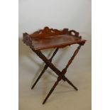 A C19th walnut butler's tray on stand, with carved and shaped gallery, the base with turned