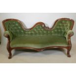 A Victorian walnut chaise longue, with shaped carved back and scroll arms, raised on scroll supports