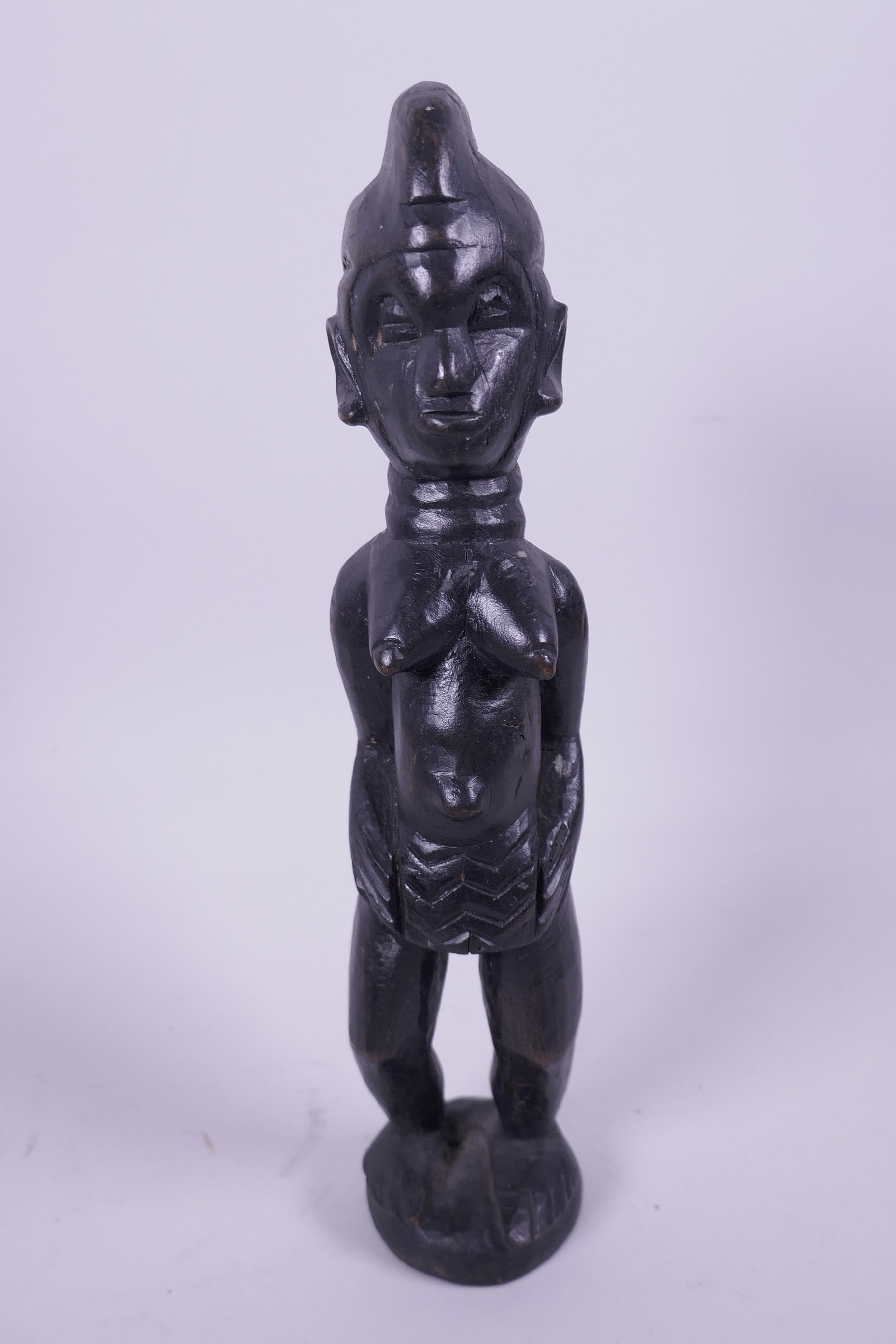 A West African carved wood figurine of a woman, 10" high