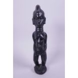 A West African carved wood figurine of a woman, 10" high