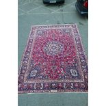 A large blue and red ground Mashad carpet with a traditional floral medallion design, 149" x 112"