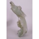 An Oriental carved green hardstone figurine of an exotic bird perched on a branch, 8½" high