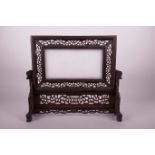 A Chinese pierced hardwood table screen containing a white jade panel with carved decoration of