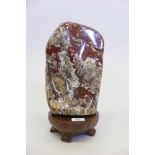 A polished stone specimen, 11" high, mounted on a wood stand