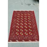 A Persian red ground Baluch nomadic carpet with a Bokhara design, 110" x 82"