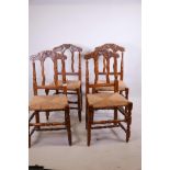A set of four C19th ash side chairs with carved backs and rush seats, raised on turned supports