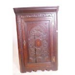 An C18th oak hanging corner cupboard with carved and inlaid decoration, 43" x 29"