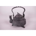 A Chinese cast bronze ceremonial teapot with embossed dragon and fish decoration, the dragon spout