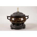A Chinese two handled bronze censer with gilt splash decoration, with carved wood cover and stand,