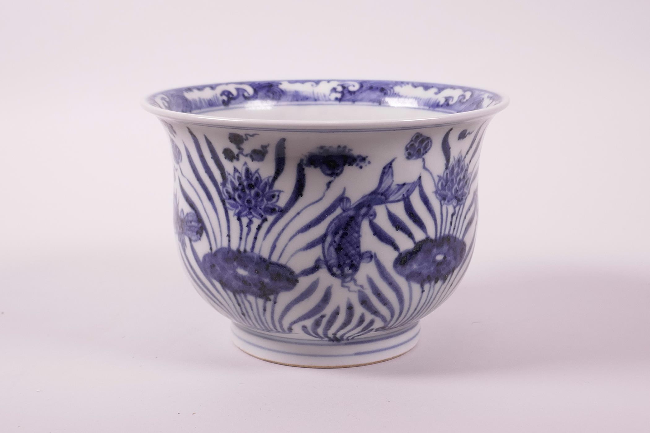 A Chinese blue and white porcelain steep sided bowl decorated with carp in a lotus pond, 4" high x