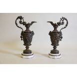 A pair of large bronze and marble ewers with raised decoration of Bacchus, the handles entwined with
