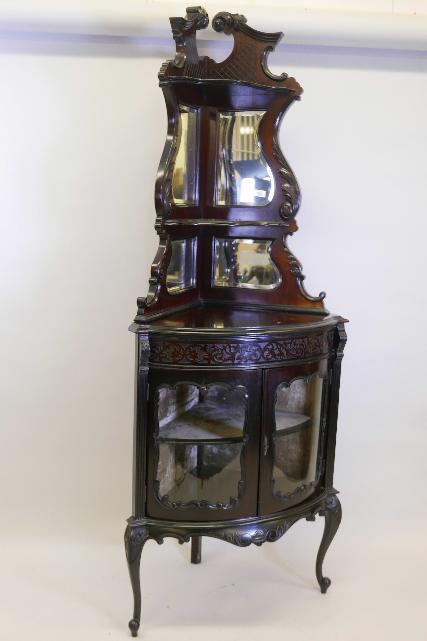 A Victorian mahogany bowfronted corner display cabinet, the upper section with mirror backed