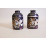 A pair of toleware canisters, decorated with painted and gilded crests, 14" high with covers