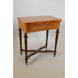 A burr walnut veneered card table with a fold over top, on fluted column legs united by an 'X'