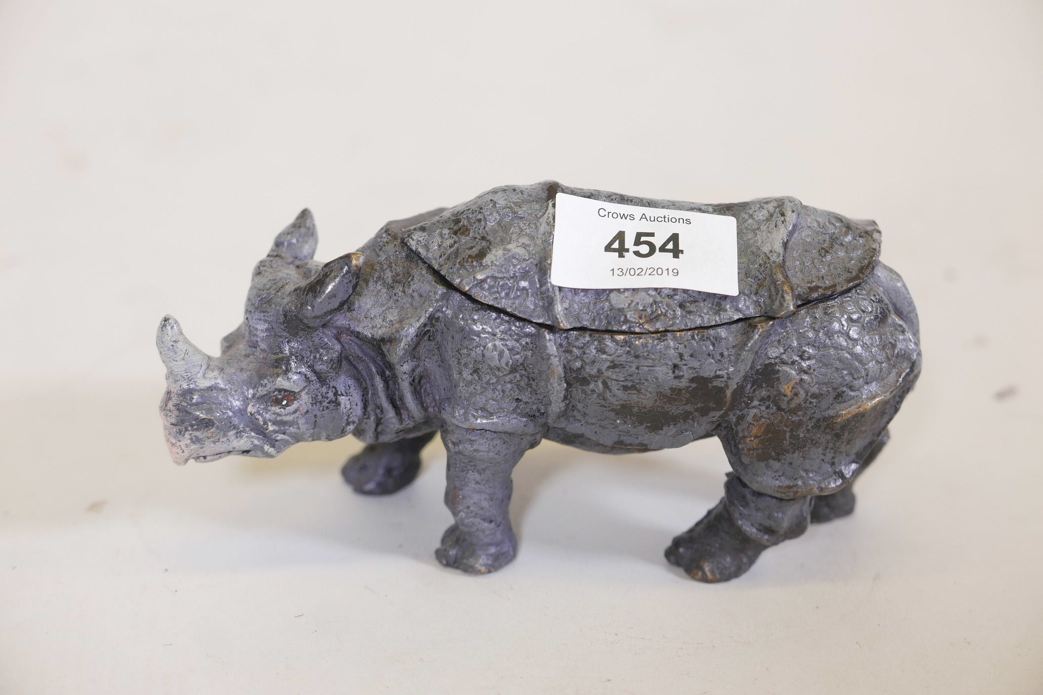 A cold painted bronze inkwell in the form of a rhinoceros, fitted with two wells, lacking liners,