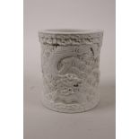 A Chinese cream ground moulded porcelain brush pot with dragon decoration, seal mark to base, 4½"