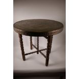 A brass topped circular occasional table on barleytwist carved folding supports, 23" high, 23½"