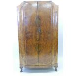 An Art Deco burr walnut shaped front press cupboard, the two doors opening to reveal three slides
