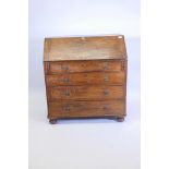 An early C19th solid elm fall front bureau, with fitted interior over four long drawers, raised on