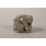 A Chinese celadon jade carving of a boy holding a lotus flower, 2" high