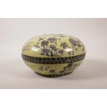 A Chinese yellow ground porcelain box and cover with black and white floral decoration, mark to