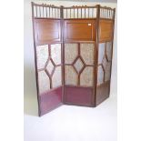 A walnut and mahogany triple fold screen with inset papier mache panels with raised floral