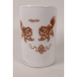 A Chinese porcelain brush pot decorated with mythical beasts, symbols in ironstone red and four