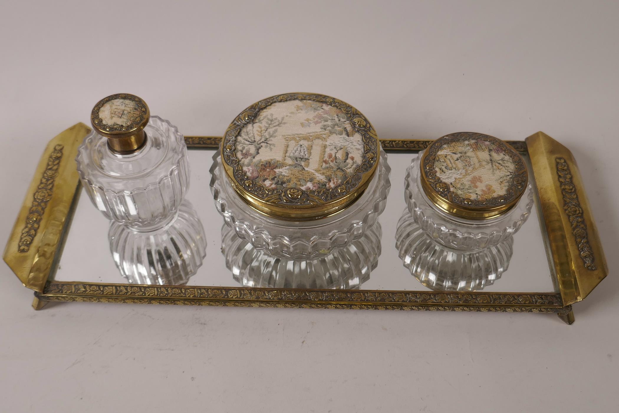 A vintage four piece brass framed dressing table set of mirrored tray and three glass bottles