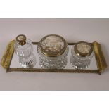 A vintage four piece brass framed dressing table set of mirrored tray and three glass bottles