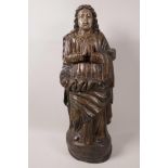 A European carved wood figurine of a saintly person at prayer, traces of old paint, 17½" high