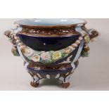 A C19th majolica jardiniere raised on four paw feet embossed with garlands, flowers and female heads