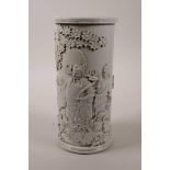 A Chinese cream ground cylinder brush pot with raised decoration of Immortals in a garden, impressed