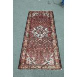 An old Persian Hamadan Luri carpet with medallion design on a tomato red field, 60" x 128"