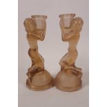 A pair of Art Deco frosted glass candlesticks moulded as kneeling girls with urns on their