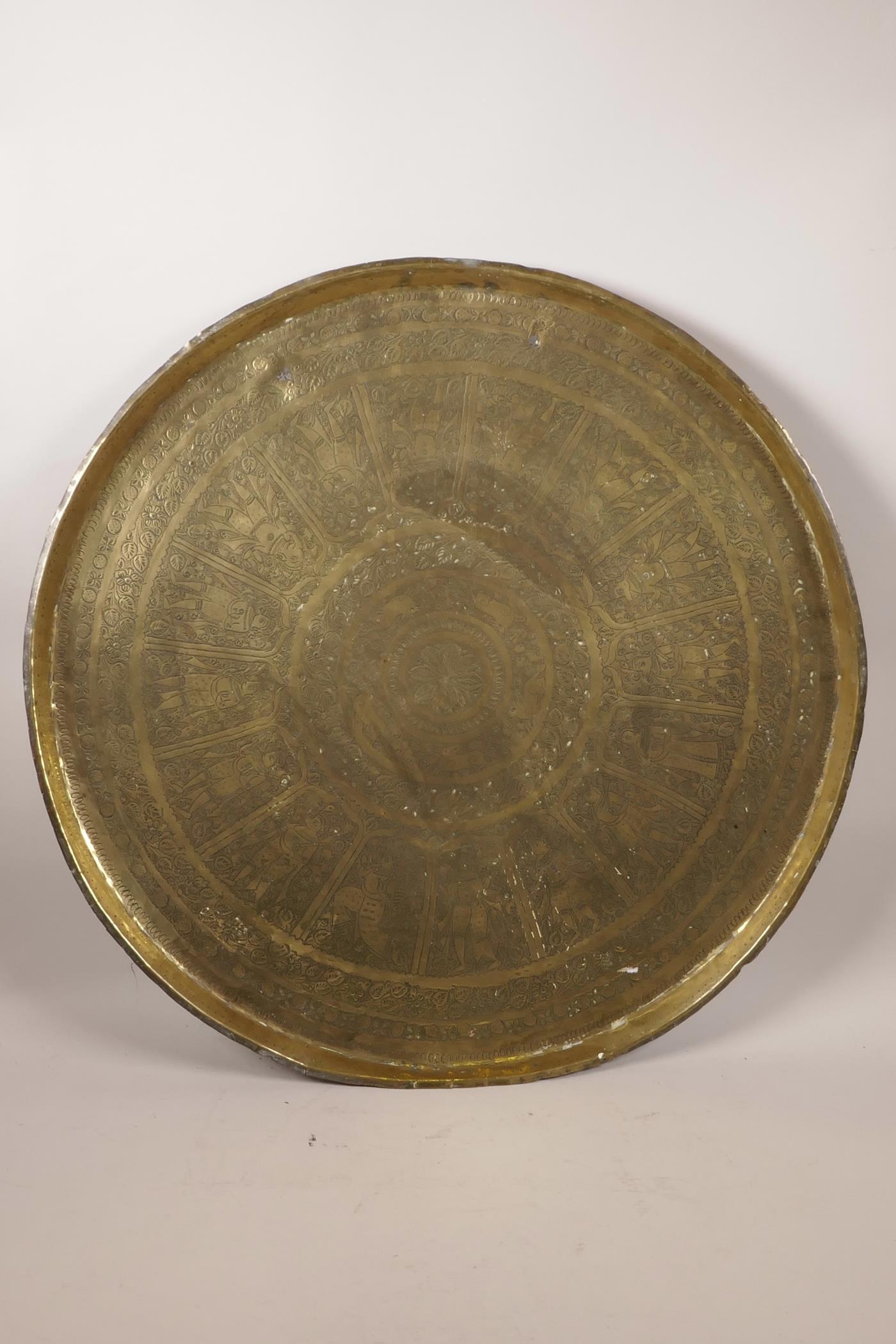 A large Indian brass tray with chased figural and animal decoration, 23" diameter