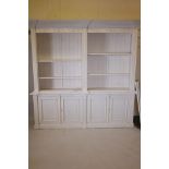 A painted bookcase, the upper section with open shelves under a decorative moulded frieze, the