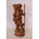 A large South East Asian carved wood figure of a female water carrier and her dog, 36" high