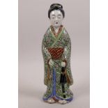 A Japanese porcelain figurine of a geisha girl in a green ground kimono, 9" high