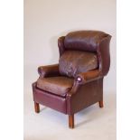 A large wing back leather upholstered armchair raised,on square supports, 45" high, 29½" wide