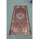 An old Persian Hamadan Luri carpet with medallion design on a tomato red field, 60" x 128"