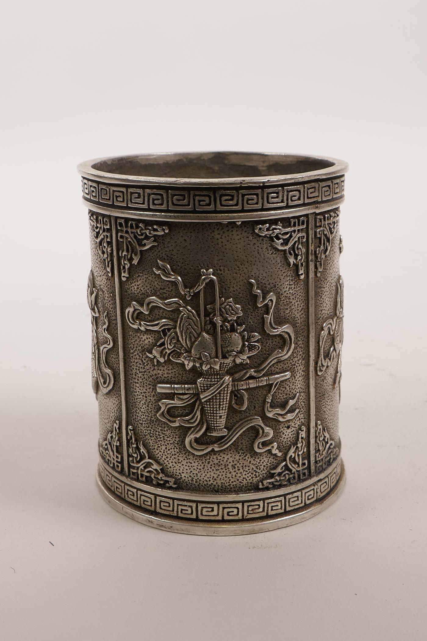 A Chinese white metal brush pot decorated with the emblems of the Eight Immortals, impressed mark to