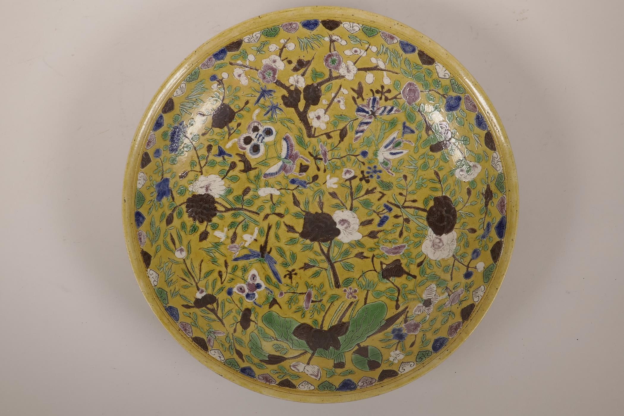 A Chinese sancai glazed porcelain charger with incised butterfly and floral decoration, 6