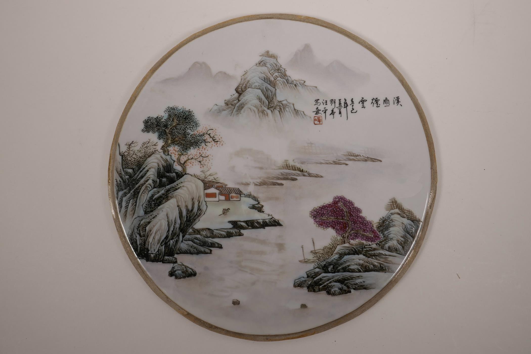 A Chinese famille verte porcelain plaque decorated with a river landscape, 10½" diameter