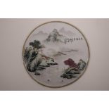 A Chinese famille verte porcelain plaque decorated with a river landscape, 10½" diameter
