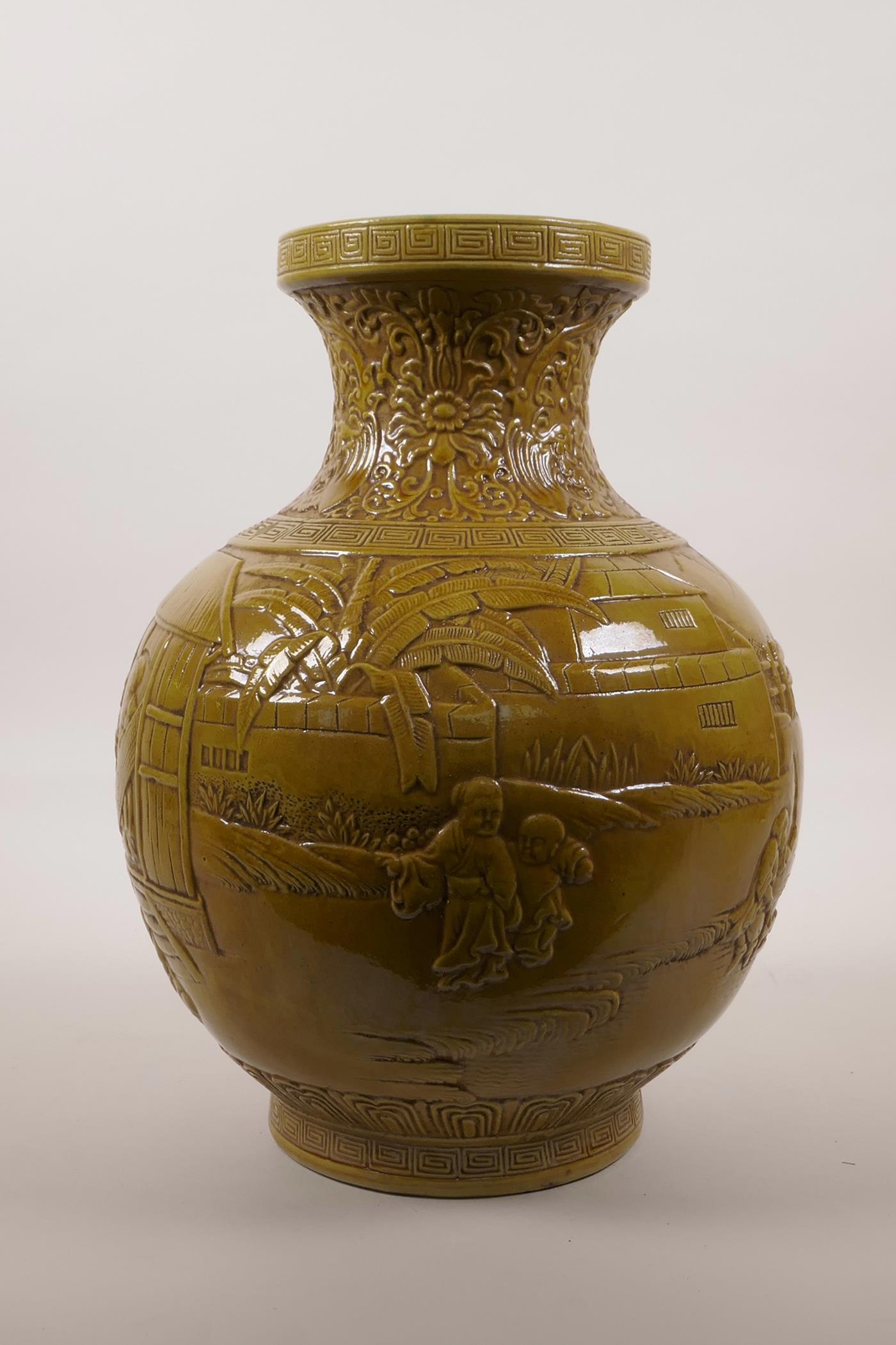 A large Chinese ochre glazed pottery vase with raised decoration of everyday village life, impressed