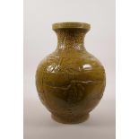 A large Chinese ochre glazed pottery vase with raised decoration of everyday village life, impressed