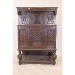 An antique oak court cupboard, the upper section with carved frieze and two cupboards, the base with