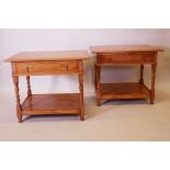 A pair of golden oak two tier side tables, with single drawers, raised on turned supports, tops