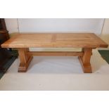 A French light oak refectory table with panelled top on twin pedestal end supports and stretcher,