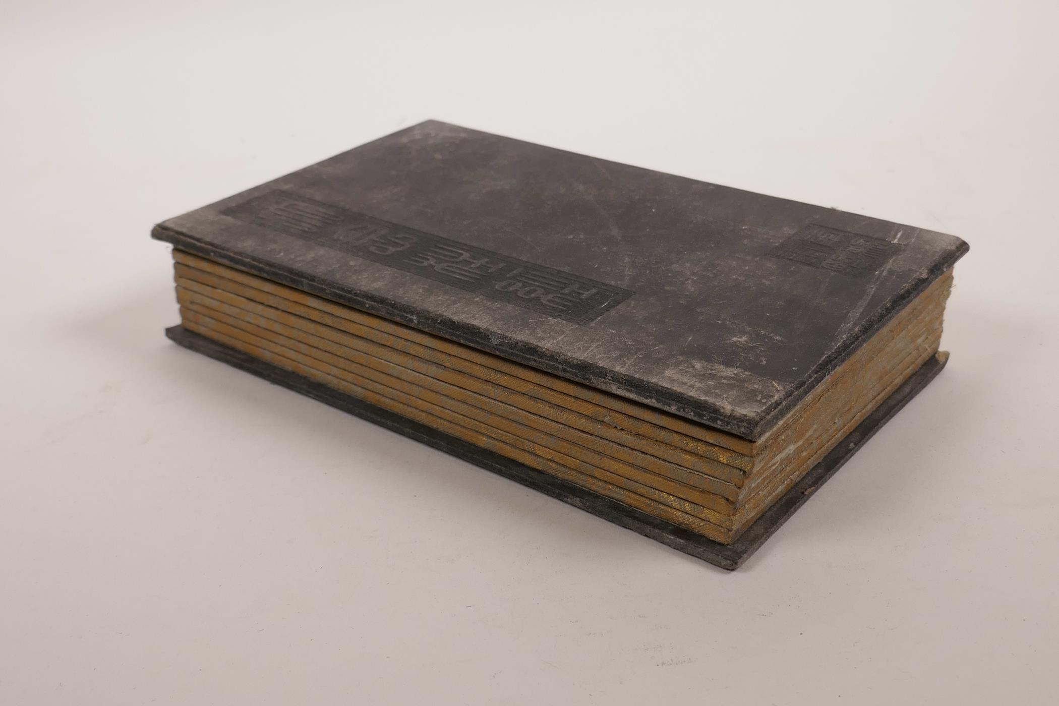 A Chinese painted wood and silk bound book containing green hardstone tablets with engraved and gilt